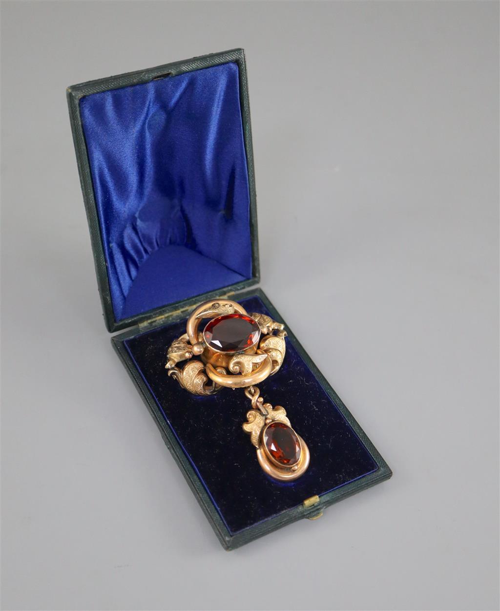 A Victorian engraved gold and two stone oval cut citrine set scrolling drop brooch,